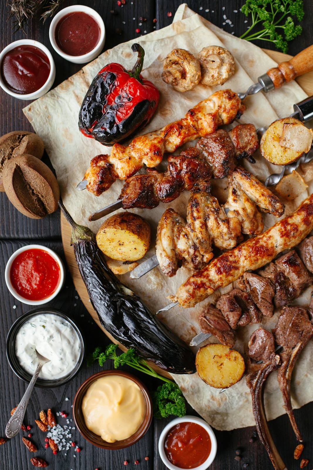 Espetos, legumes grelhados e molhos sobre a mesa