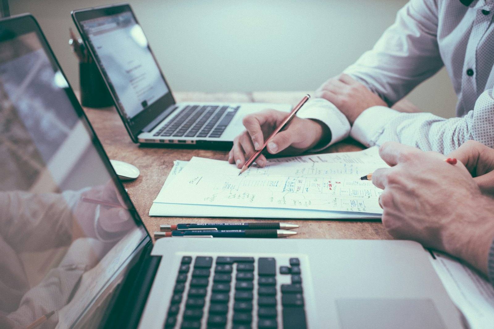 Pessoas trabalhando com notebooks e anotações